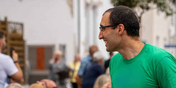 Daniel Jalalpoor steht vor einer Hecke und krempelt sich die Hemdärmel hoch.